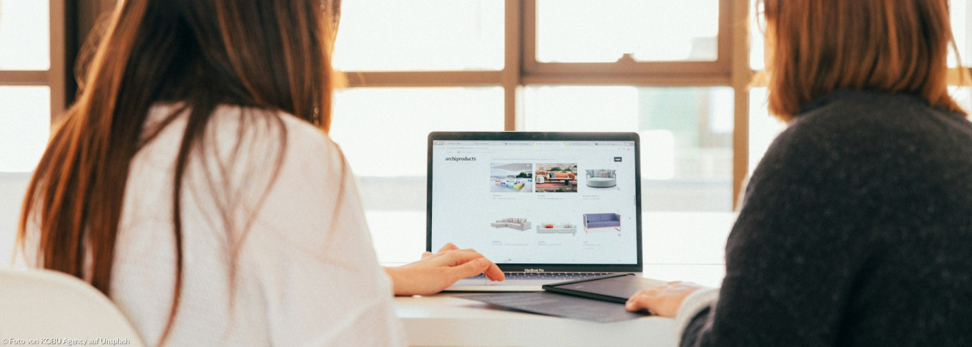 Zwei Frauen unterhalten sich, während sie auf einen Laptop schauen